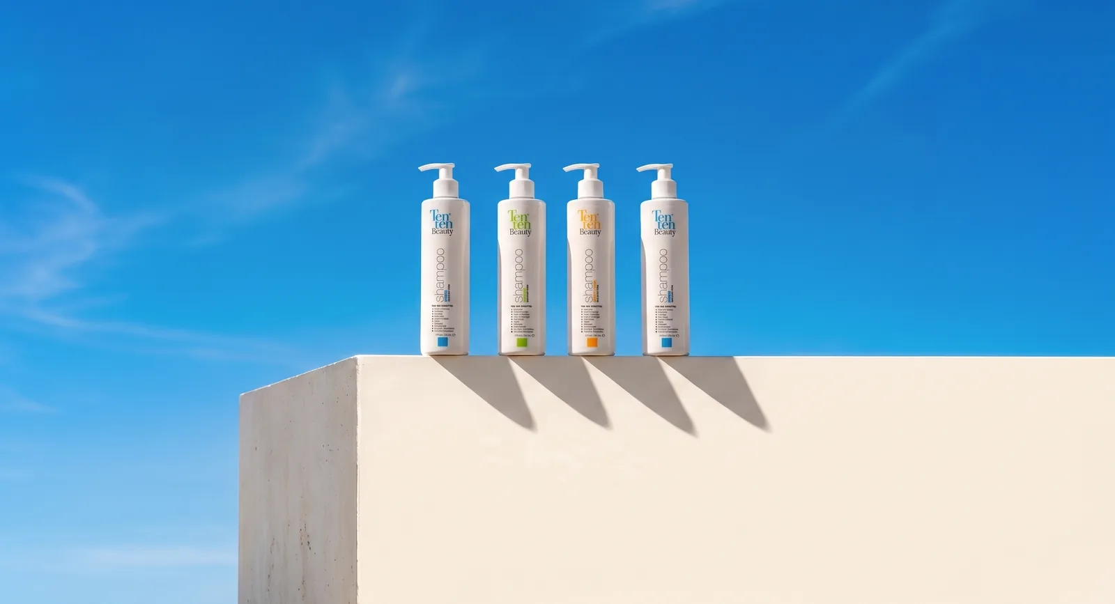 Los cuatro shampoos Ten Ten Beauty alineados sobre una repisa clara contra cielo azul