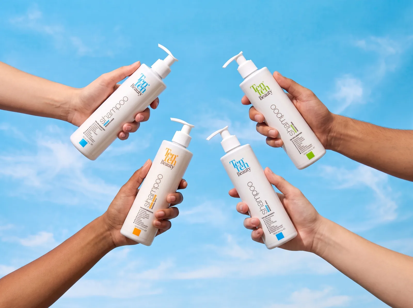 Cuatro manos sosteniendo shampoos Ten Ten Beauty contra cielo azul